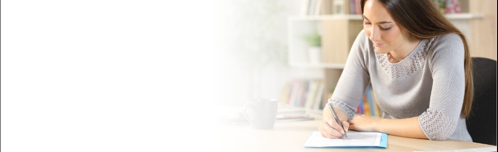 Woman sitting at desk filling out a paper survey with a pen